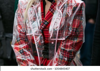 MILAN - FEBRUARY 22: Woman with red tartan jacket and transparent raincoat before Fendi fashion show, Milan Fashion Week street style on February 22, 2018 in Milan.