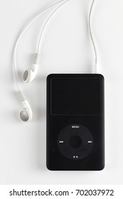 Milan, Italy - 10/02/2012: close up on a classic iPod 80 GB resting on a white background. Apple headphones are also visible.