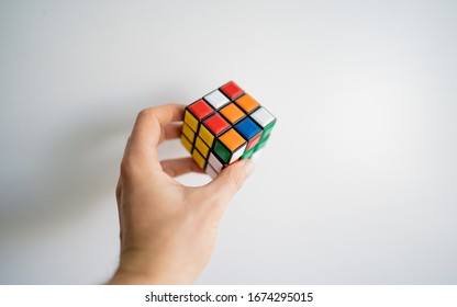 MILAN, ITALY: 13 March 2020: Cube in child's hands, closeup, top view, white wooden background. Boy holding cube and playing with it. During home quarantine for Coronavirus.  - Shutterstock ID 1674295015