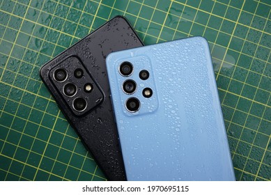 Milan, Italy - 17 April 2021: Samsung Galaxy A52 in Blue Color and Galaxy A72 in Black color, New Midrange  Smart Phones from Korean Company with Drop Waters on it, IP67 Water Resistance