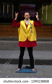 Milan, Italy - 3/9/2019: Woman Silently Protesting The Persecution Of The Falun Gong In China, Standing On A Street In The Downtown Area