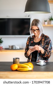 Milan, Italy - April 2020: Young Italian Woman Smart Working And Enjoying An Espresso Coffee At Home, During Lockdown. Scrolling Her Phone While Having Breakfast Looking For News About The Cover-19.