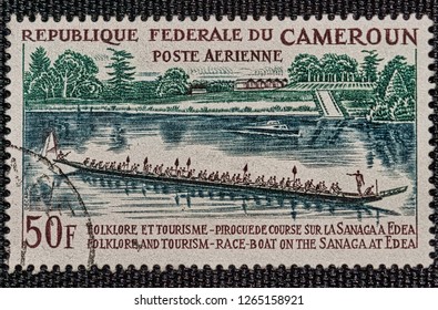 MILAN, ITALY - DECEMBER 23, 2018: A Stamp Of Federal Republic Of Cameroon Shows A Race With A Pirogue. Stamp With Postmark.