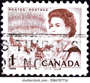 Milan, Italy, December 6, 2021: Postage Stamp Printed In Canada In 1971 That Queen Elizabeth II, Northern Lights And Dog Sled Team.