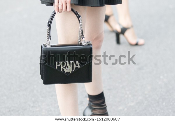 Milan, Italy - February\
21, 2019: Model wears a pleated black miniskirt and a black leather\
Prada handbag during the Prada show for the spring / summer 2020\
collection