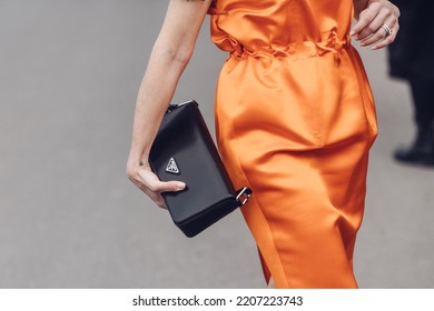 Milan, Italy - February 24, 2022: Street Style, Woman Wearing Orange Prada Long Dress, Prada Black Bag, Prada Loafers.