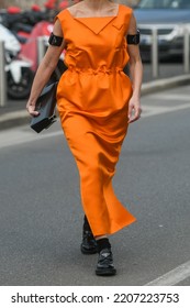 Milan, Italy - February 24, 2022: Street Style, Woman Wearing Orange Prada Long Dress, Prada Black Bag, Prada Loafers.