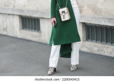 Milan, Italy - February, 24: Street Style, Woman Wearing A Dark Green Coat, A White Handbag, White Pants, Snake Print Pattern Ankle Boots.