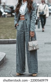 Milan, Italy - February, 24: Street Style, Woman Wearing White Cropped Shirt, A Gray Blazer Jacket, Gray Matching Suit Pants, A Beige Leather Handbag And Yellow Green Open Toe-cap Pumps Sandals.