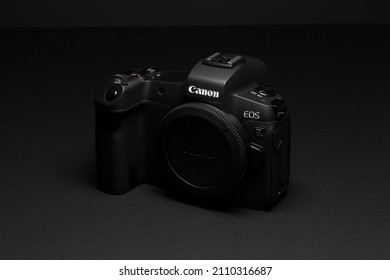 Milan, Italy - January 1, 2022: close up on Canon EOS R mirrorless camera resting on a black background and shot with light painting, no people are visible.