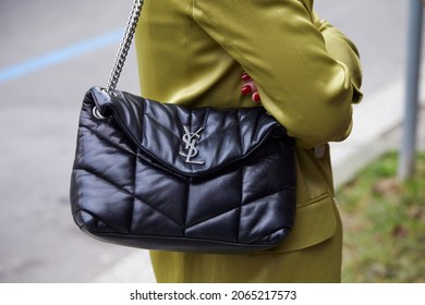 MILAN, ITALY - JANUARY 14, 2019: Woman with black leather Yves Saint Laurent bag and green satin dress, street style
