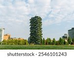 Milan, Italy - July 15, 2023: Vertical forest - Two residential towers, on the facade terraces of which trees, shrubs and grass paths are planted. Modern skyscraper district in Milan. Summer day