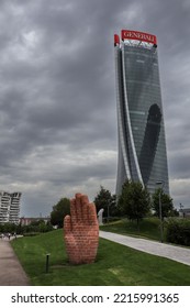 Milan, Italy - June 26, 2022: Modern Generali Building In Tre Torri With Hand Sculpture. CityLife Architecture During Dramatic Cloudy Day In Lombardy.