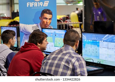 Milan, Italy - March 8 2019 Cartoomics Comic Con Visitors Play FIFA 19 EA Sports Game With Cristiano Ronaldo Poster At The Background