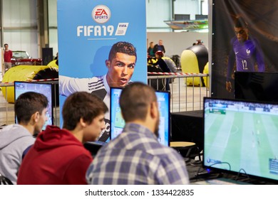 Milan, Italy - March 8 2019 Cartoomics Comic Con Visitors Play FIFA 19 EA Sports Game With Cristiano Ronaldo Poster At The Background In Focus