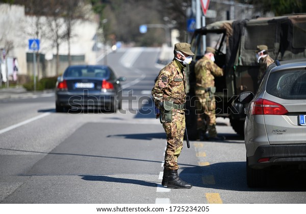 MILAN, ITALY - MAY 8, 2020. Military soldier\
controls. Security patrol with masks and gloves monitor passing\
motorists. Daily street control for the Covid-19 global crisis. The\
army at work.