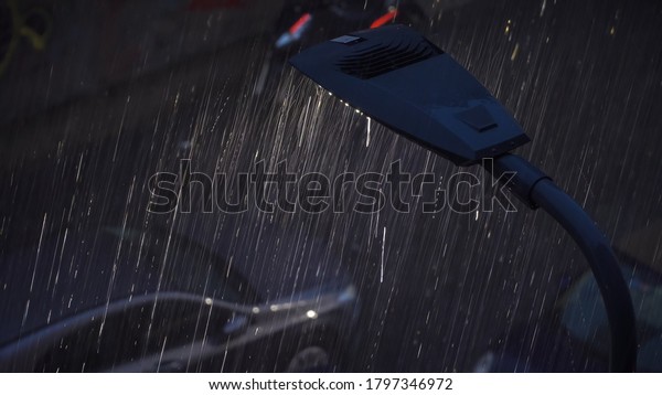 Milan, Italy. Night city in rainy weather. Cars\
passing on the wet asphalt of city streets. Traffic lights at\
night. Reflection in puddles on the ground. Crossroads at night.\
food delivery bike. \
