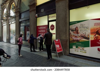 Milan, Italy - November 18 2021: open pharmacy store entrance conducting Covid-19 rapid tests. External day view of Italian pharmaceutical shop with sign and crowd in line for a quick swab.