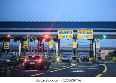 Milan, Italy - November 23, 2018: Cars Pass Through Illuminated Telepass Toll Gates On Italian Highway At Dawn.
