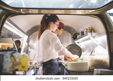 MILAN, ITALY - NOVEMBER 7: People visiting Eat Market, a street food parade with international dishes  in Milan on November, 7 2015. Woman and man chef cooking for customer inside food truck