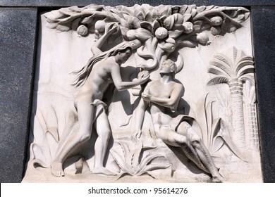 Milan, Italy. Old Biblical Scene Sculpture At The Monumental Cemetery (Cimitero Monumentale). Religious Art Depicting Adam And Eve Picking The Fruit In The Garden Of Eden.