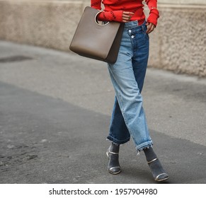 Milan, Italy - September 22, 2018: Fashionable woman wearing blue jeans and red Balenciega sweater on the streets of Milan, detail.