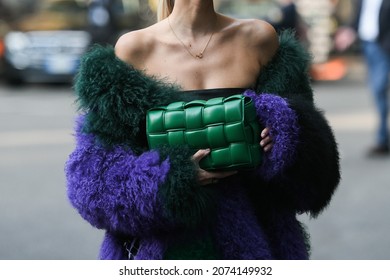 Milan, Italy - September 23, 2021:  Street style outfit, fashionable woman wearinga cropped t-shirt, a green shiny leather Cassette handbag from Bottega Veneta and an oversized fluffy coat.