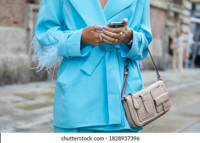 MILAN, ITALY - SEPTEMBER 24, 2020: Woman with blue jacket with feathers looking at smartphone