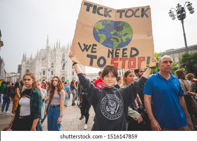 Milan, Italy – September 27, 2019: student holding "We need to stop" picket signs at “Fridays For Future” climate change strike protest  in downtown Milan