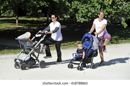 MILAN, ITALY-SEPTMEBER 13, 2014: mothers with stroller making healthy exercise with a fitness trainer in a city garden park, in Milan