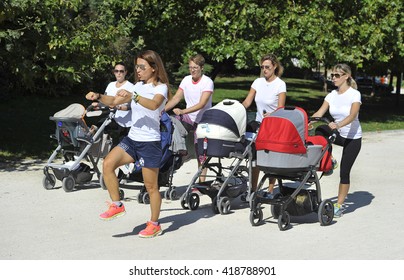 MILAN, ITALY-SEPTMEBER 13, 2014: mothers with stroller making healthy exercise with a fitness trainer in a city garden park, in Milan