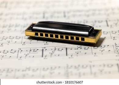 Milan, Lombardy, Italy - July 21, 2020 : Mouth organ or harmonica on a music score