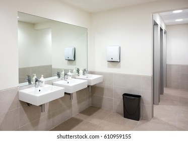 Milan, Lombardy, Italy - March 09,2017 : Public Restaurant Bathroom With A Row Of Three Hand Basins With Soap Dispensers Below A Large Mirror And Neutral Beige Tiled Decor