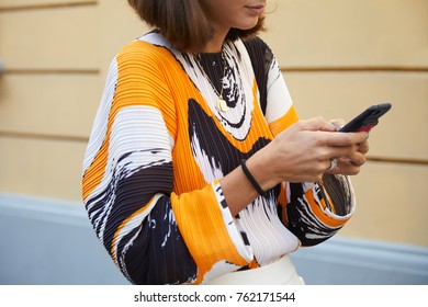 MILAN - SEPTEMBER 22: Woman With Orange, Black And White Shirt Looking At Smartphone Before Sportmax Fashion Show, Milan Fashion Week Street Style On September 22, 2017 In Milan.