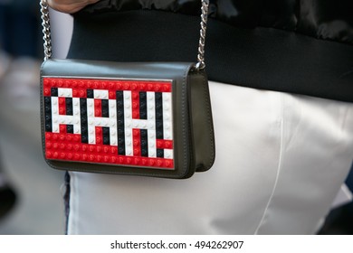 MILAN - SEPTEMBER 25: Woman with bag with red and white Lego writing Ah! before Salvatore Ferragamo fashion show, Milan Fashion Week street style on September 25, 2016 in Milan.