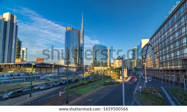 Milan skyline with modern\
skyscrapers in Porta Nuova business district timelapse  in Milan,\
Italy, at sunset with orange light. Traffic on the road. Top view\
from bridge