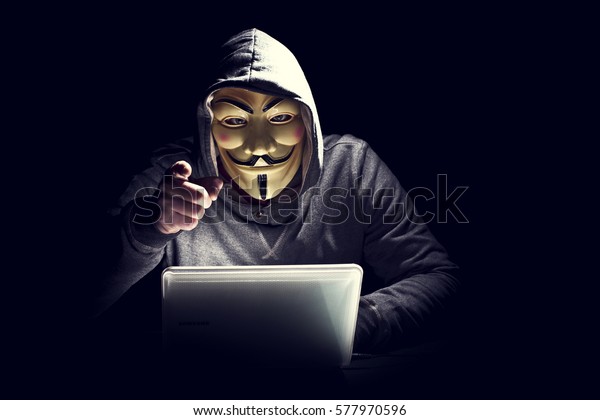 MILAN,ITALY, February, 2017: Hacker\
wear anonymus mask with notebook in the dark .Editorial\
photo.