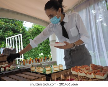 MILANO, ITALY - Jul 07, 2021: A Waitress Wearing A Covid Mask, Serving Food In A Buffet At A Private Wedding Event