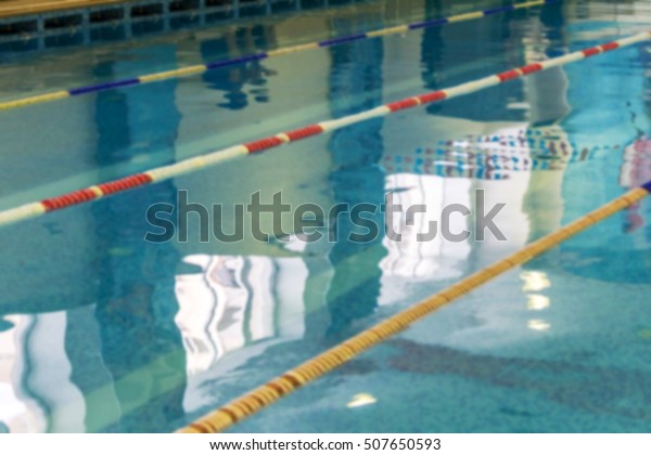 Mild blurred background Sports Swimming Pool. Bath\
Interior sports pool, divided swimming lanes for swimmers, tables\
to start during the competition. Mild background without focus as\
blank for design