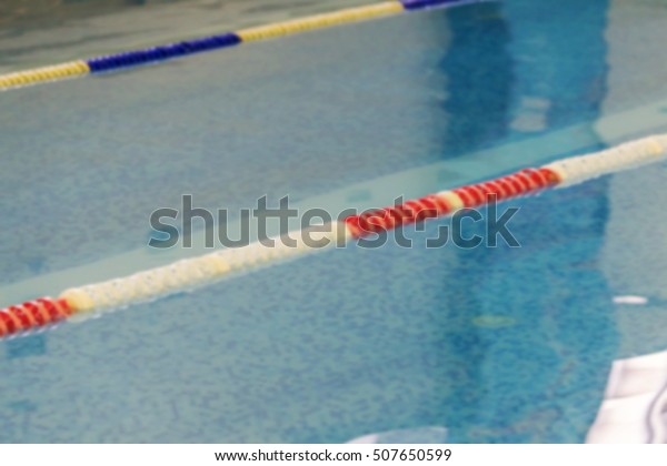 Mild blurred background Sports Swimming Pool. Bath
Interior sports pool, divided swimming lanes for swimmers, tables
to start during the competition. Mild background without focus as
blank for design