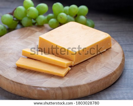 Mild Red Cheddar Cheese on wooden board with grapes