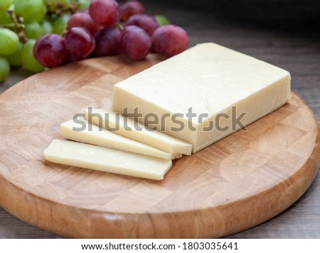 Mild white cheddar on wooden board with grapes