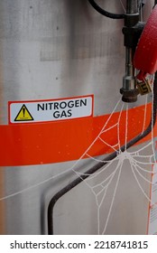 MILDENHALL, UNITED KINGDOM - Jan 16, 2013: The Vertical View Of A Frozen Cobweb On The Silver Tank With A Nitrogen Gas Warning Sign