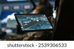 Military agent working in control room, using software on tablet, analyzing aerial reconnaissance data. Close up of intelligence corps expert controlling drones with portable device, camera A