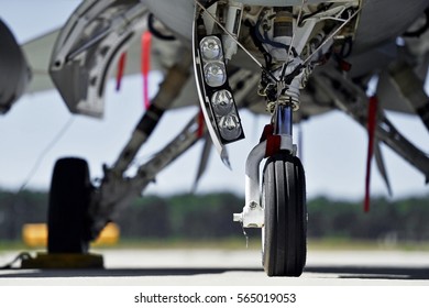Military aircraft detail with landing gear and engine cover on a runway