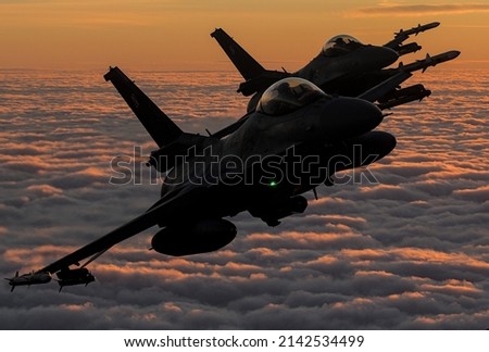 Military aircraft during sunset flying over the clouds