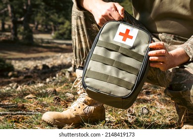 Military army first aid kit. Camouflaged soldier medic. White and red first aid sign.