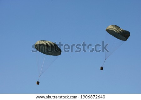 Military army parachutes paratroopers equipment in blue sky from airplane. Armed Forces special battalion staff exercise. National defense concept, security.