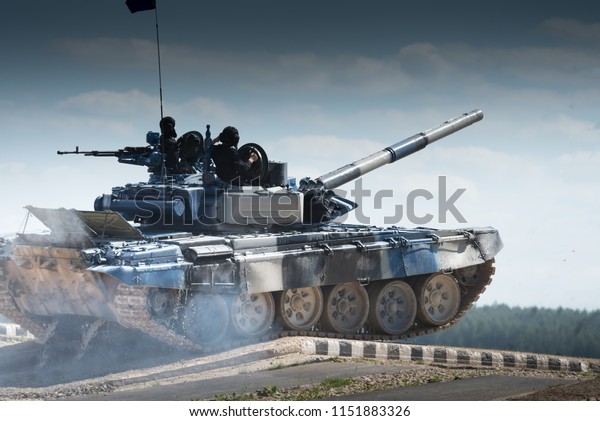 Military or army tank ready to attack and\
moving over a deserted battle field\
terrain.