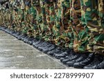 Military boots and camouflage trousers of many soldiers in uniform in a row under the rain